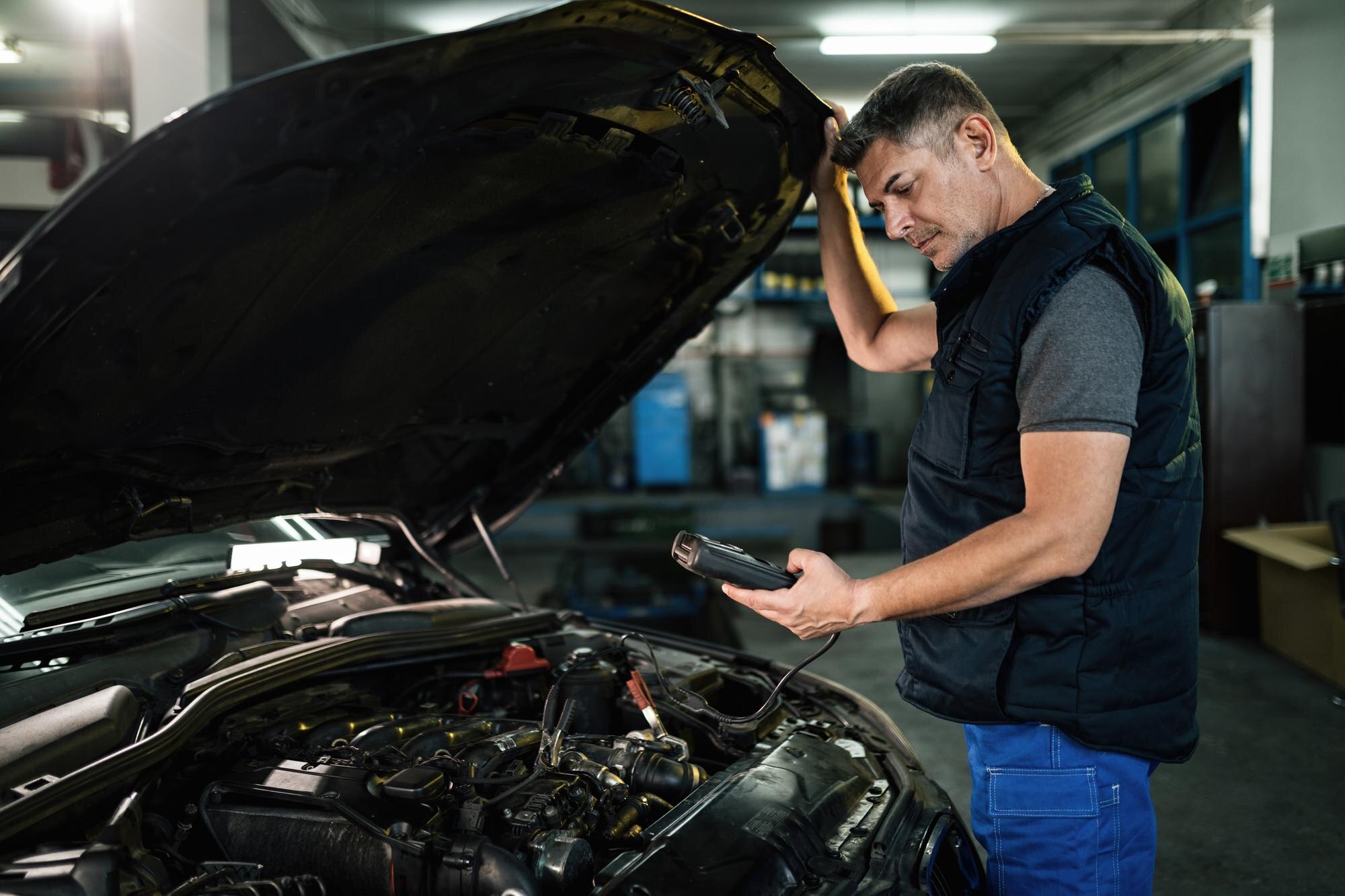 auto mechanic using diagnostic work tool while checking car engine workshop