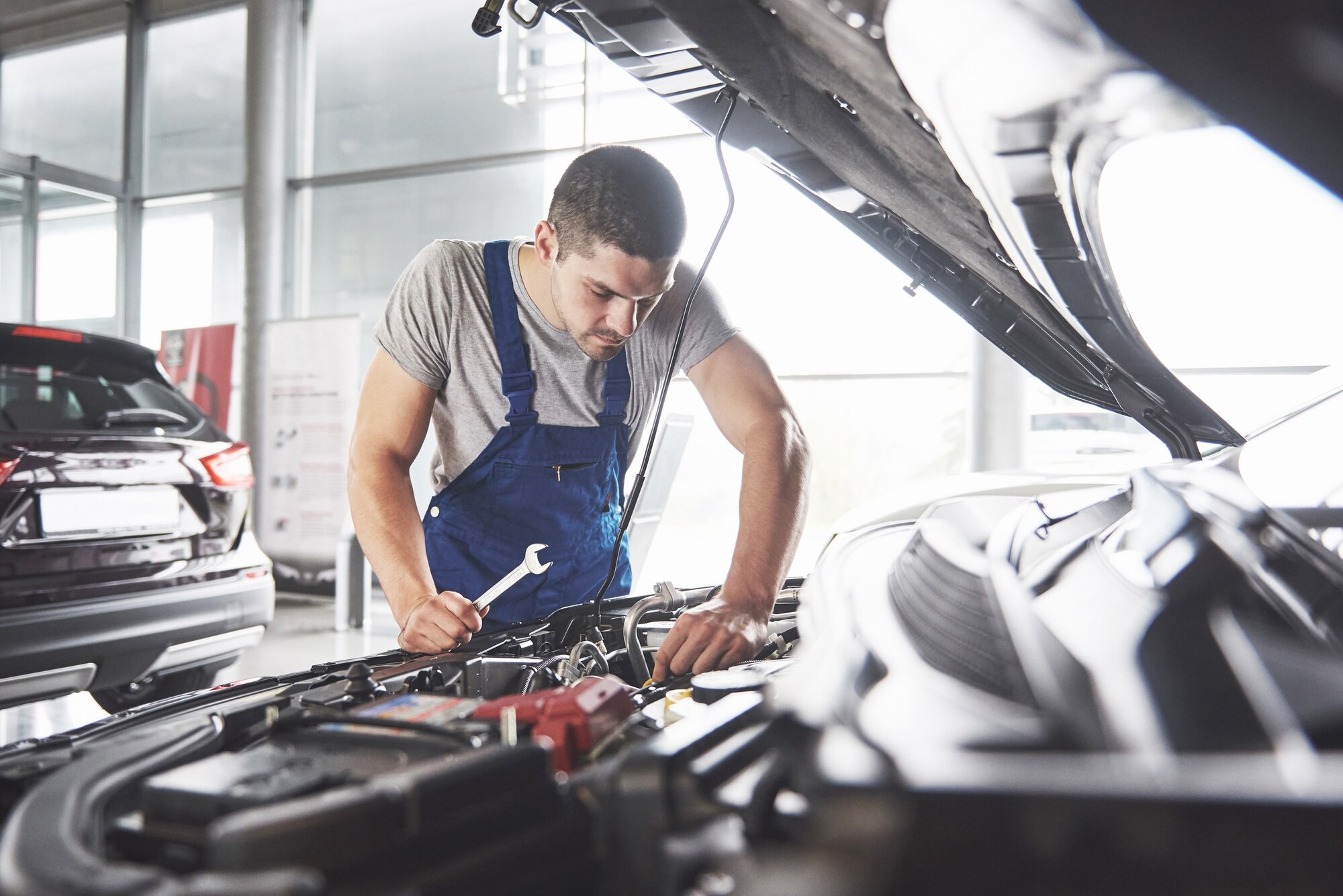 muscular car service worker repairing vehicle
